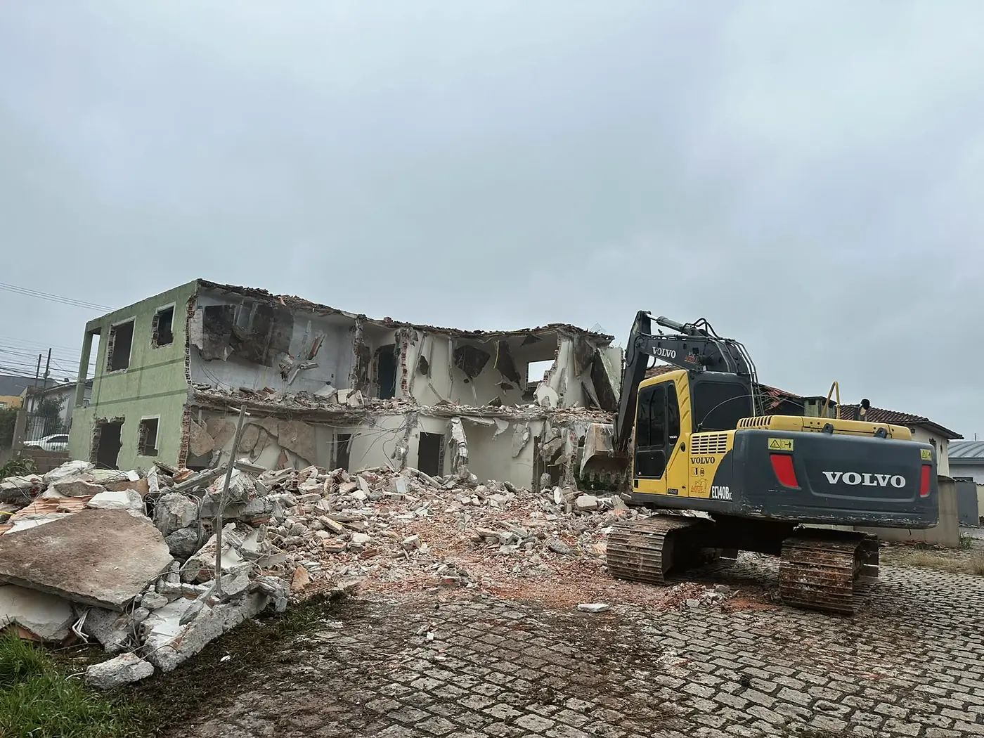 Escavadeira Volvo sobre o entulho de um imóvel demolido, pronta para a carga