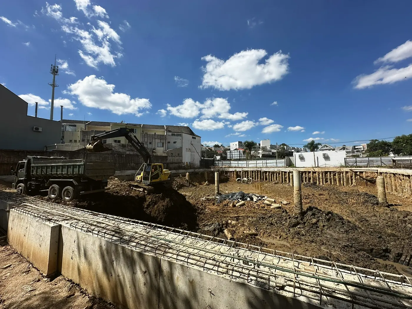 Escavadeira carregando a terra de um subsolo no caminhão basculante da Andrade