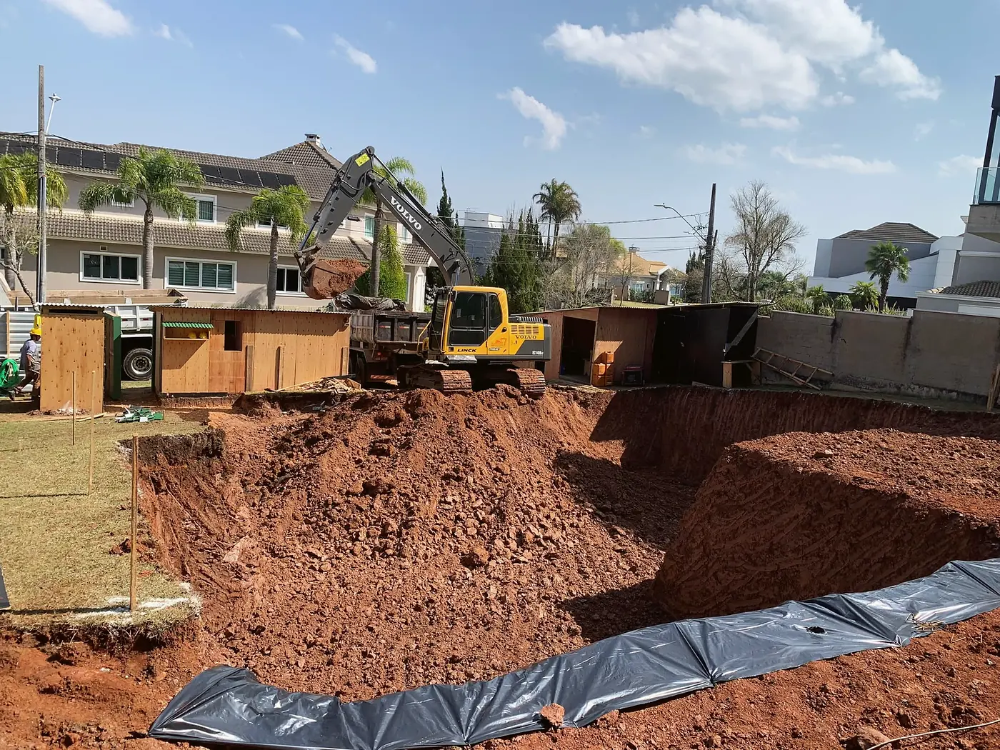 Cava de subsolo aberta e protegida com lona em terreno urbano